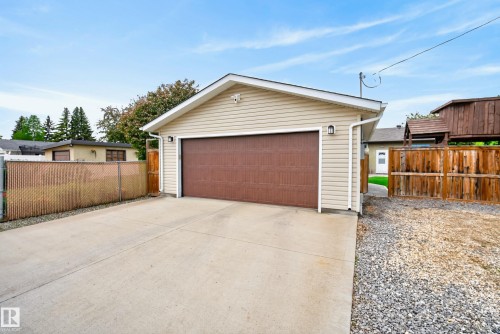 Detached garage with tan siding, a brown garage door, and a concrete driveway - 16105 109A Avenue, Edmonton, AB 