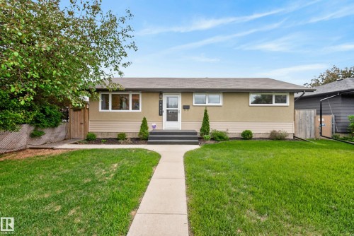 Single-story residence featuring a stucco and siding exterior, a front entry with black steps, a concrete walkway, and a manicured lawn - 16105 109A Avenue, Edmonton, AB 