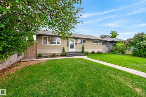 Single-story residence featuring a stucco and siding exterior, front yard with a concrete walkway, mature lawn, and foundational plantings - 16105 109A Avenue, Edmonton, AB 