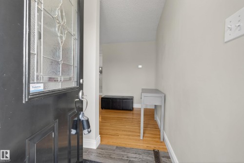 Entryway with wood-finish flooring, light grey wall paint, and a decorative frosted glass front door - 16105 109A Avenue, Edmonton, AB 