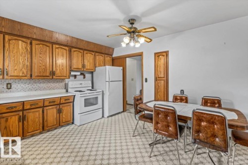 Kitchen featuring wood cabinetry, white countertops, a mosaic tile backsplash, and a patterned floor - 12923 113A Street, Edmonton, AB 