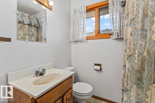 Bathroom featuring a wood-finish vanity with an integrated sink and chrome faucet - 12923 113A Street, Edmonton, AB 
