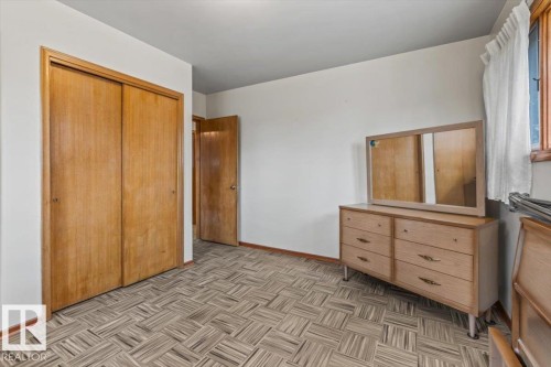 Room featuring patterned tile flooring, wood-finish bi-fold closet doors, and painted white walls - 12923 113A Street, Edmonton, AB 