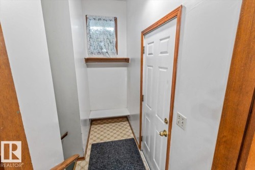 Entryway featuring a paneled door with brass hardware, wood-finish trim, and patterned floor tiles - 12923 113A Street, Edmonton, AB 