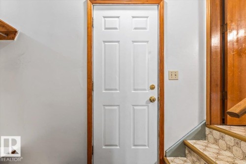 White paneled door with brass hardware, framed by natural wood trim - 12923 113A Street, Edmonton, AB 