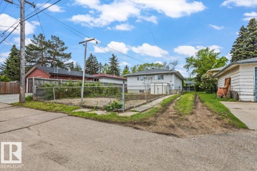 Rear exterior featuring a detached garage with siding, an unpaved driveway, and a fenced garden area - 12923 113A Street, Edmonton, AB 