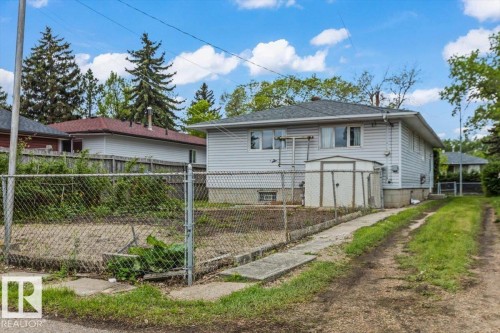 Vinyl-sided residence featuring a gray roof, rear entry, and ground-level windows - 12923 113A Street, Edmonton, AB 