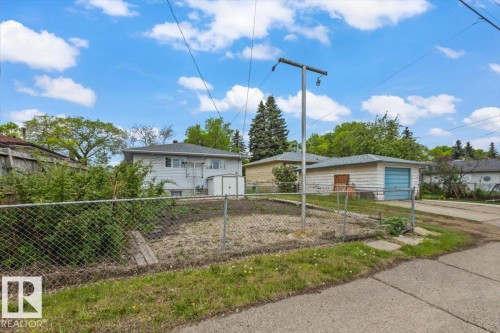 Chain link fenced lot featuring a concrete driveway and adjacent garage structure - 12923 113A Street, Edmonton, AB 