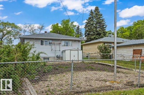 Rear exterior featuring horizontal siding, multiple windows, and a detached shed - 12923 113A Street, Edmonton, AB 