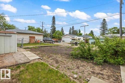 Expansive backyard area featuring a detached storage shed, chain-link fencing, and a concrete pathway - 12923 113A Street, Edmonton, AB 
