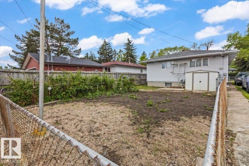 Rear exterior featuring white vinyl siding, a gray shingle roof, and multiple windows - 12923 113A Street, Edmonton, AB 