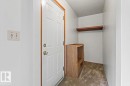 Entryway with a white paneled door featuring brass hardware, wood trim, and a wall-mounted light switch - 12923 113A Street, Edmonton, AB 