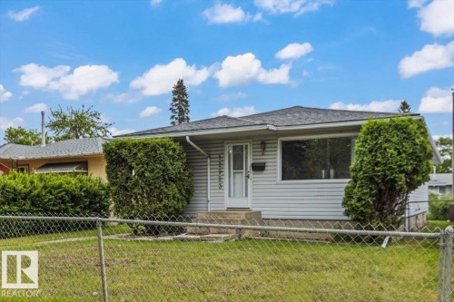 Ranch-style residence featuring light-colored siding, a dark shingle roof, and a front entry door with a storm door - 12923 113A Street, Edmonton, AB 