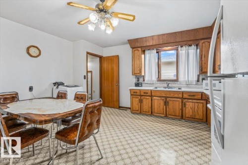 Kitchen featuring wood-finish cabinetry, white countertops, a single-basin sink, and patterned flooring - 12923 113A Street, Edmonton, AB 