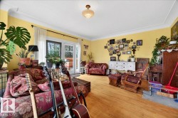 Bright living area featuring wood-finish flooring, a decorative ceiling light fixture, and crown molding - 