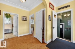 Hardwood flooring throughout a bright hallway with white trim, featuring multiple paneled doors and an arched doorway - 