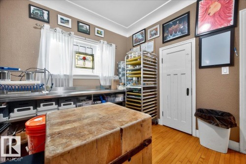 Hardwood flooring and a large butcher block island define this space, featuring stainless steel countertops, a window with decorative stained glass, and a paneled door - 572004 Highway 857, Rural Two Hills County, AB 