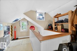 Attic space featuring dormer windows, sloped ceilings, beadboard half-walls, a wood-finish railing, and built-in wood shelving - 