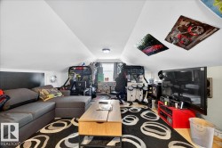 Attic space featuring sloped ceilings, a window, and wood-finish flooring - 