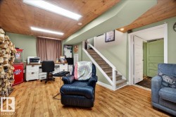 Finished lower level featuring wood-finish flooring, wood plank ceiling, recessed lighting, a built-in desk, and a carpeted staircase - 