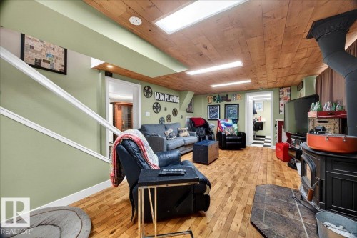 Recreation room featuring wood-finish flooring, a wood stove with a slate hearth, and a wood plank ceiling with recessed lighting - 572004 Highway 857, Rural Two Hills County, AB 