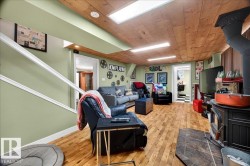 Recreation room featuring wood-finish flooring, a wood stove with a slate hearth, and a wood plank ceiling with recessed lighting - 