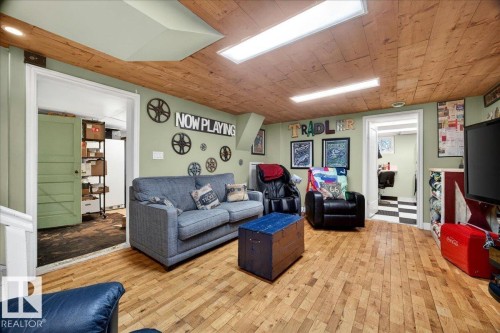 Recreation room featuring paneled wood-finish ceiling, light green walls, and wood-finish flooring - 572004 Highway 857, Rural Two Hills County, AB 