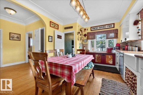 Dining area featuring wood-finish flooring, an arched doorway, and a linear pendant light fixture - 572004 Highway 857, Rural Two Hills County, AB 