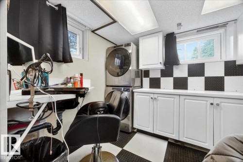 Utility space featuring white cabinetry, a light-colored countertop, and a black and white checkerboard backsplash - 572004 Highway 857, Rural Two Hills County, AB 