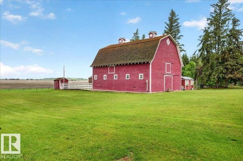 Red barn structure featuring a gambrel roof and white trim accents - 572004 Highway 857, Rural Two Hills County, AB 