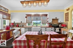 Kitchen featuring white beadboard cabinetry, wood-finish countertops, and a farmhouse sink - 
