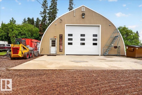 Quonset-style building with a large white roll-up door featuring multiple windows - 572004 Highway 857, Rural Two Hills County, AB 