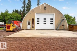 Quonset-style building with a large white roll-up door featuring multiple windows - 