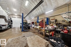 Spacious, high-ceiling structure featuring a large overhead door, an automotive lift, and ample workspace - 