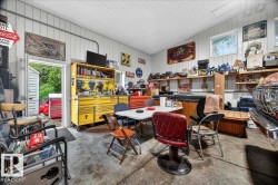 Spacious utility building featuring corrugated metal walls and ceiling, exposed conduit, concrete flooring, and multiple shelving units - 
