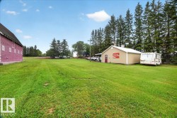 Expansive green lawn with a red-sided barn and a tan-sided outbuilding - 