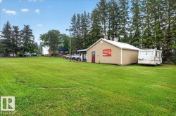 Spacious green lawn with a detached auxiliary building featuring a shed roof and a red entry door - 