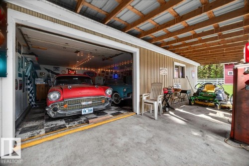 Detached garage featuring an exposed beam ceiling, corrugated metal roofing, an overhead door, and a dedicated storage area with a window - 572004 Highway 857, Rural Two Hills County, AB 