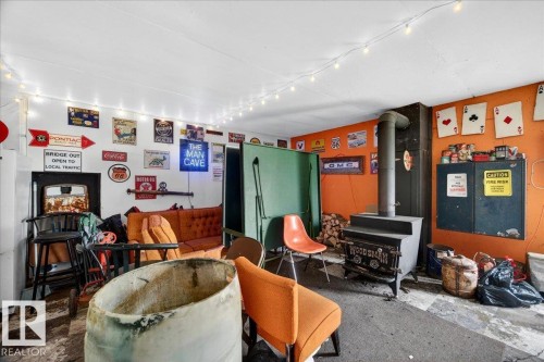 Utility room with a wood-burning stove, white and orange painted walls, and concrete flooring - 572004 Highway 857, Rural Two Hills County, AB 