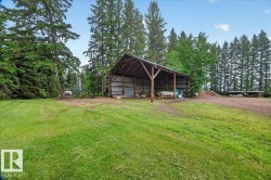 Open-sided barn structure featuring a metal roof and wooden support beams - 