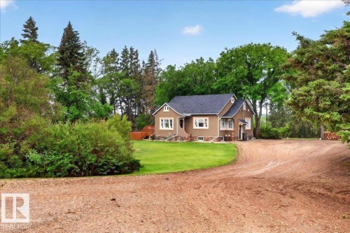 Stucco exterior residence featuring a dark shingle roof, white-trimmed windows, and stone detailing on the foundation - 572004 Highway 857, Rural Two Hills County, AB 
