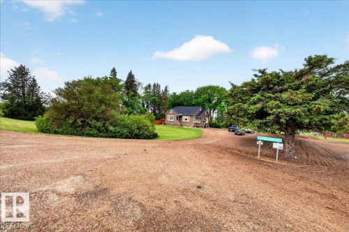 Expansive gravel driveway leading to a residence featuring a tan exterior and dark roof - 572004 Highway 857, Rural Two Hills County, AB 
