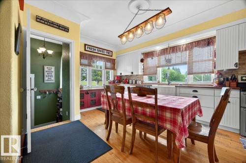 Kitchen featuring hardwood flooring, white cabinetry, a farmhouse sink, and a rustic light fixture - 572004 Highway 857, Rural Two Hills County, AB 