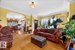 Living space featuring wood-finish flooring, an arched doorway, and crown molding - 