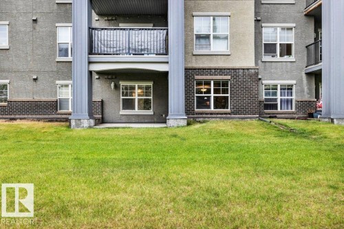 Expansive green lawn fronting a multi-story building featuring stucco and brick finishes - 116 630 Mcallister Loop, Edmonton, AB 