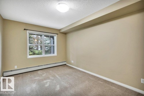 Interior room featuring neutral wall paint, light brown carpeting, and white baseboards - 116 630 Mcallister Loop, Edmonton, AB 