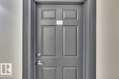Panel-style entry door in a gray finish, featuring a silver-toned doorknob and lever handle - 116 630 Mcallister Loop, Edmonton, AB 
