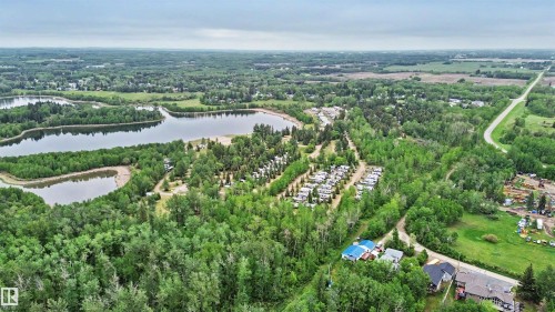 Expansive aerial perspective showcasing a lake with surrounding wooded areas and a recreational vehicle park - 337 Smith Crescent, Rural Parkland County, AB 