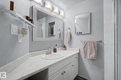 Bathroom vanity featuring an oval undermount sink, brushed nickel faucet, and a light-toned countertop - 308 10933 124 Street, Edmonton, AB 