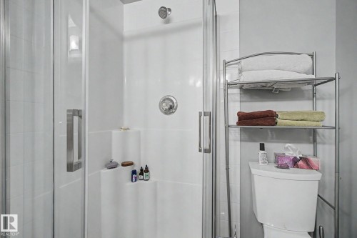 White tiled shower enclosure with a glass door and brushed chrome hardware - 308 10933 124 Street, Edmonton, AB 
